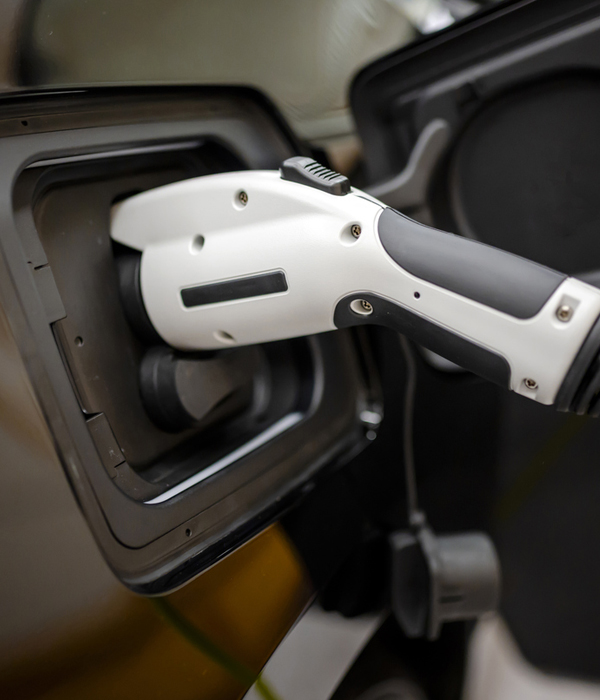 Close-up view of an electric vehicle charging connector plugged into a car during EV charger installation.