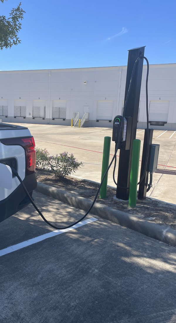 Bidirectional EV charging station installed in a commercial parking lot, connected to an electric vehicle for efficient power transfer and charging.