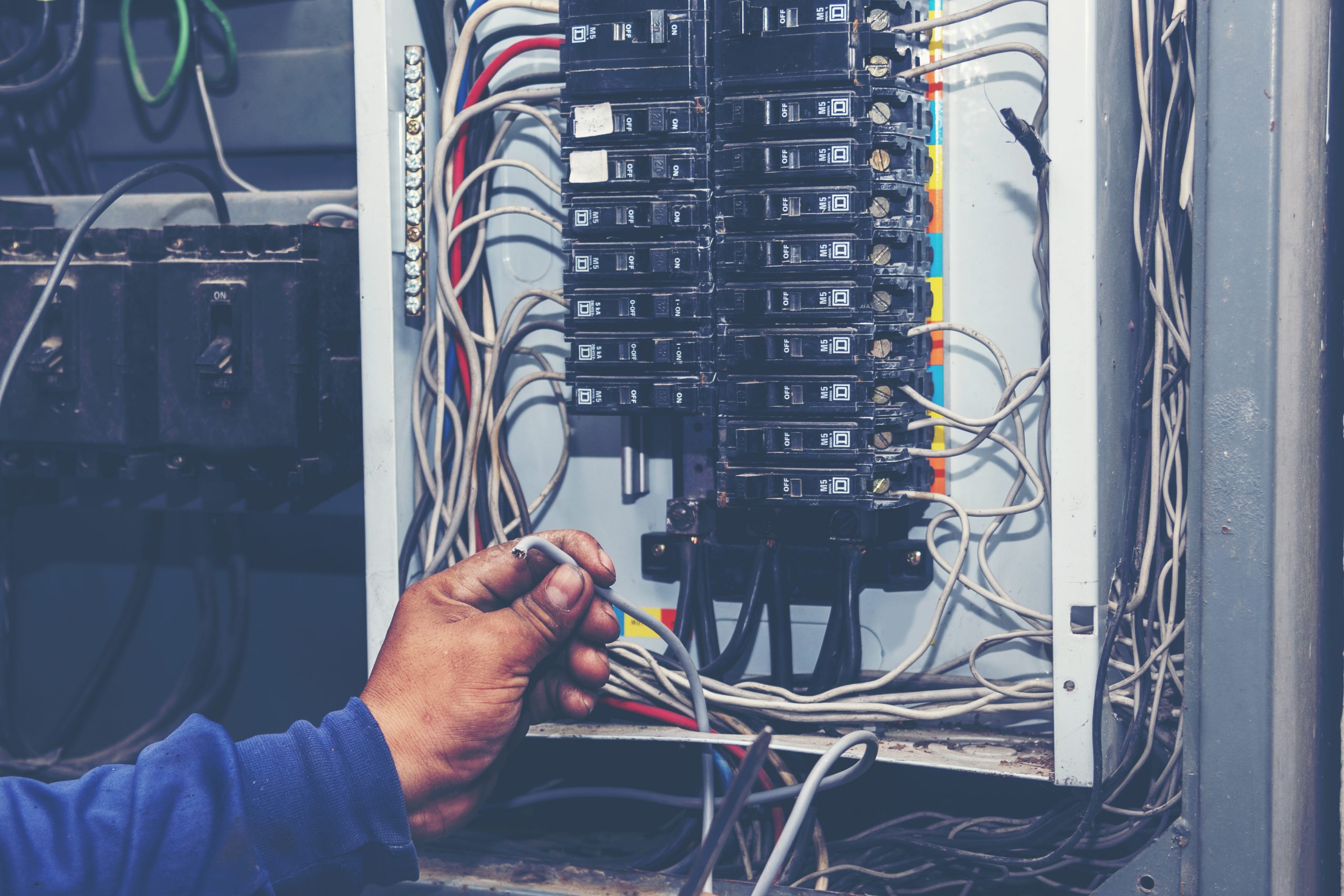 Electrician working on a residential breaker panel during an electrical panel upgrade, providing safe electrical load and proper panel capacity for home electrical safety.
