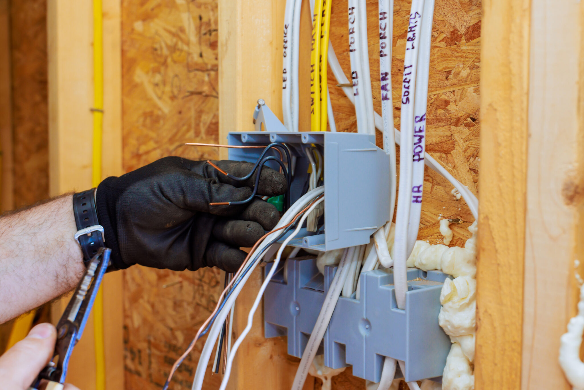 Electrician connecting wires inside a wall-mounted electrical box during a residential wiring project.