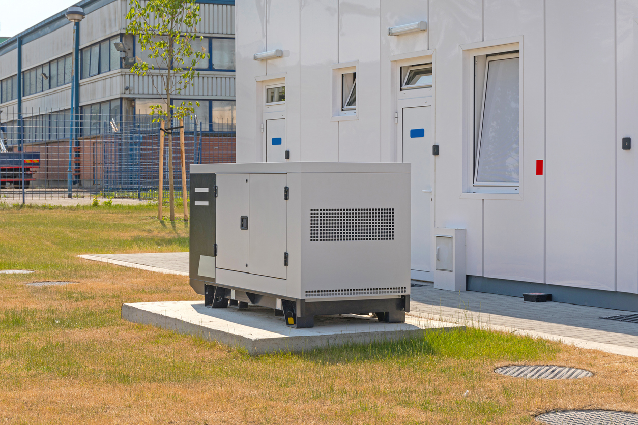 Outdoor backup generator unit on a concrete pad beside a commercial building in the Houston area.