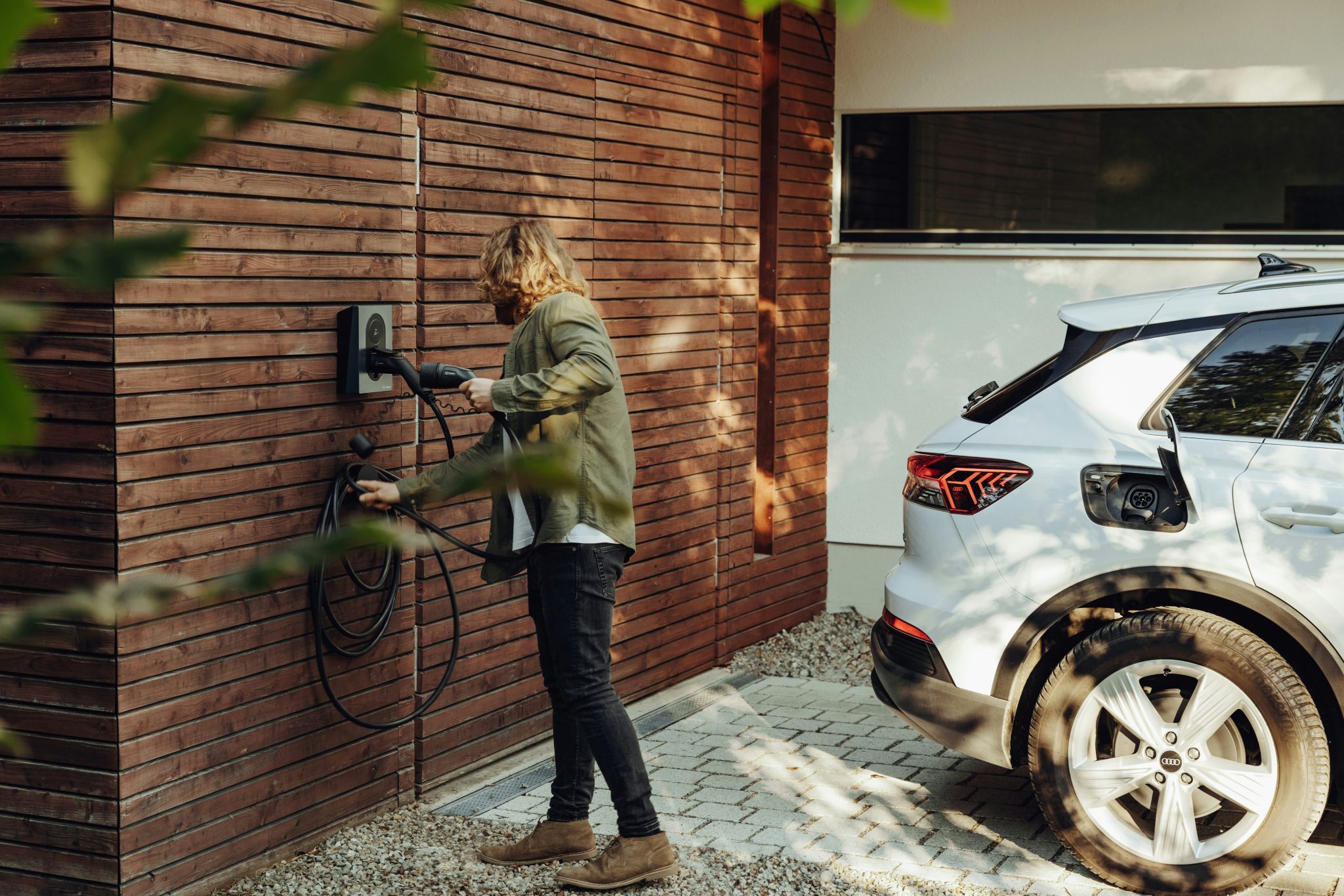 A woman is using a bidirectional EV charger at home to charge her vehicle.